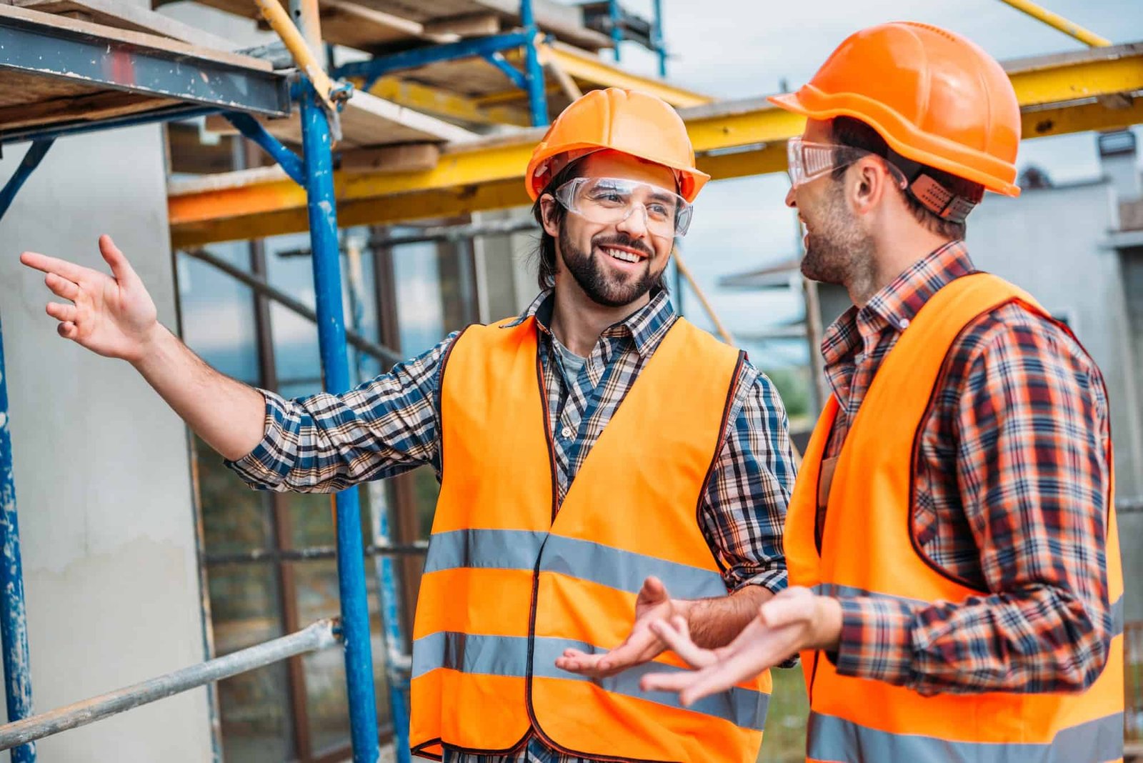 happy-builders-in-reflective-vest-and-hard-hat-pointing-at-building-house.jpg
